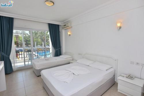 a bedroom with two beds and a balcony at Tunan Motel in Ayvalık