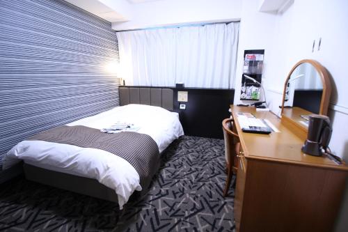 彦根市にあるアパホテル　彦根南のベッドとデスクが備わるホテルルームです。
