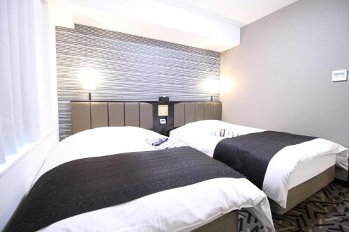 two beds in a room with a window at APA Hotel Hikoneminami in Hikone