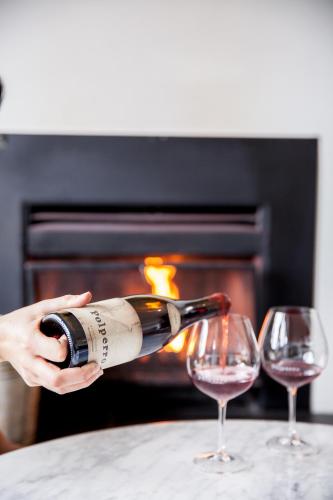 a person pouring a glass of wine in front of a fireplace at Polperro Villas in Red Hill