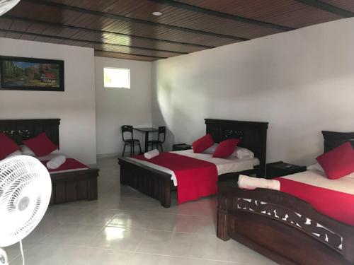 a bedroom with two beds with red pillows at Hotel campestre la Maria in Villavicencio