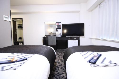 a hotel room with two beds and a flat screen tv at APA Hotel Hikoneminami in Hikone