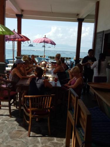 a group of people sitting at tables in a restaurant at Puri Oka Beach Bungalows in Candidasa