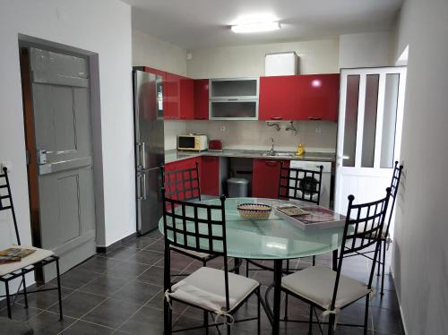 cocina con armarios rojos, mesa y sillas en Sleep & Go Faro Airport Guest House, en Faro