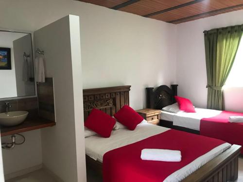a bedroom with two beds and a sink and a mirror at Hotel campestre la Maria in Villavicencio