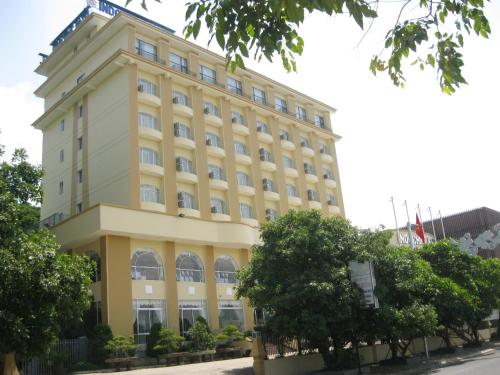 a large yellow building with trees in front of it at Indochine Hotel in Kon Tum
