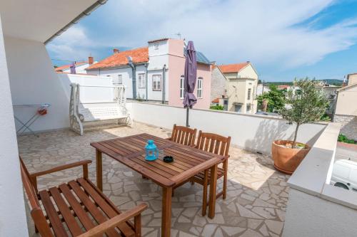 a patio with a wooden table and chairs on a balcony at Apartments Leonardo in Primošten