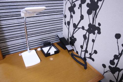 a desk with a lamp and a phone on it at APA Hotel Hikoneminami in Hikone