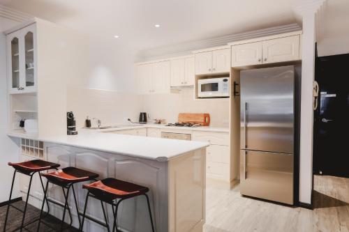 a kitchen with a refrigerator and two bar stools at Camden Apartment in Camden