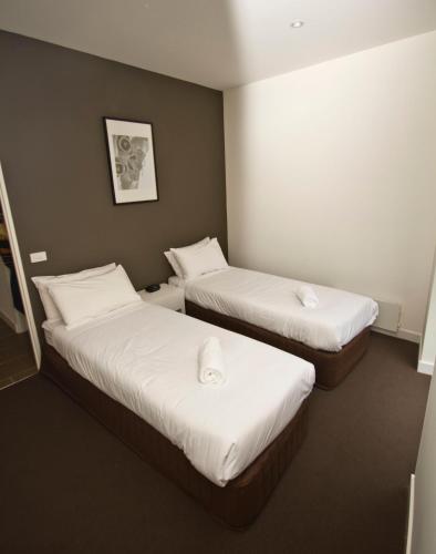 two beds in a hotel room with white sheets at St Falls West 101 in Falls Creek