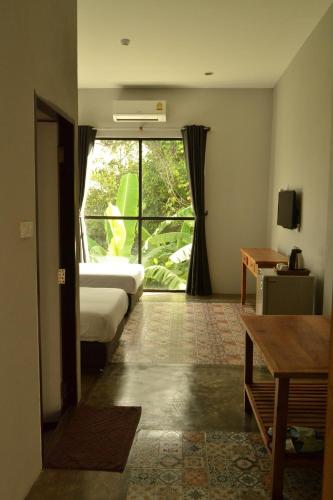 a room with two beds and a large window at Nornlamphun Boutique Hotel นอนลำพูน in Lamphun