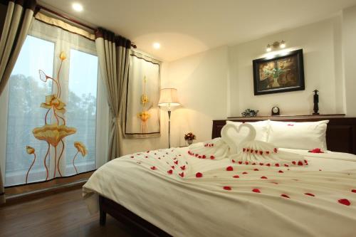 a bedroom with a large white bed with roses on it at Hanoi Siva Luxury Hotel & Travel in Hanoi