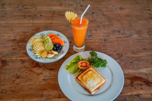 un tavolo con due piatti di cibo e un bicchiere di succo d'arancia di Ina Inn ad Ubud