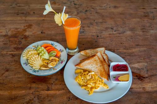 un tavolo con due piatti di cibo e un bicchiere di succo d'arancia di Ina Inn ad Ubud