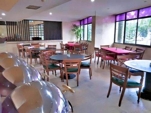 a dining room with tables and chairs and windows at Ratu Mayang Garden in Pekanbaru