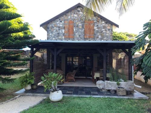 a stone house with a porch and a patio at La grange de G. in Grand Gaube