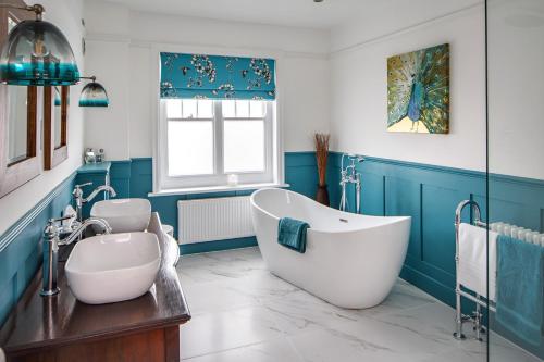 a blue bathroom with a tub and a sink at Alton House Sheringham in Sheringham