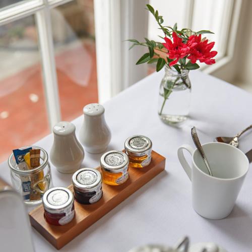 einen Tisch mit Honiggläsern und einer Blumenvase in der Unterkunft Alton House Sheringham in Sheringham