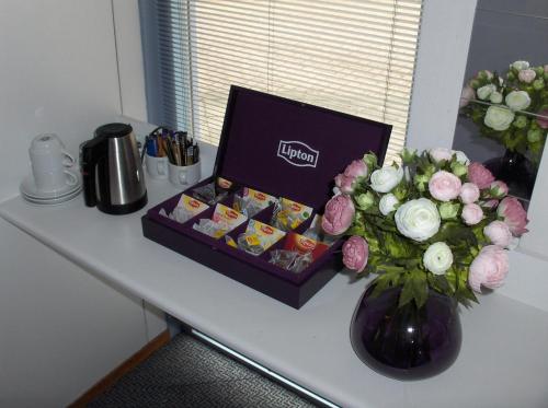 una mesa con una caja de dulces y un jarrón de flores en B&B Zevenkamp, en Róterdam