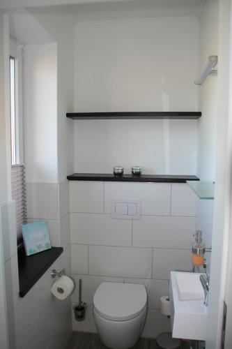 a white bathroom with a toilet and a sink at Holunder Hüsken in Oberlangen