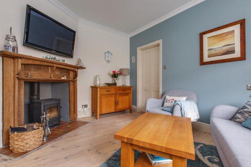 a living room with a fireplace and a tv at Alton House - The Annexe in Sheringham