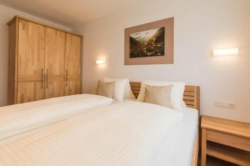 a bedroom with two beds and a wooden cabinet at Apartment im Huggn in Fulpmes