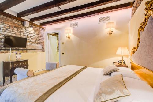 a bedroom with a large bed and a tv at Hotel Al Duca Di Venezia in Venice