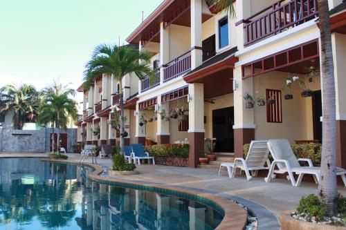 a hotel with a swimming pool in front of a building at Organgrinder Thai Paradise South in Cha Am