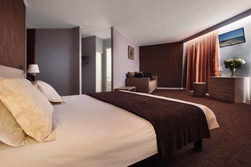 アンティーブにあるHôtel de l'Étoileの大きなベッドとソファが備わるホテルルームです。