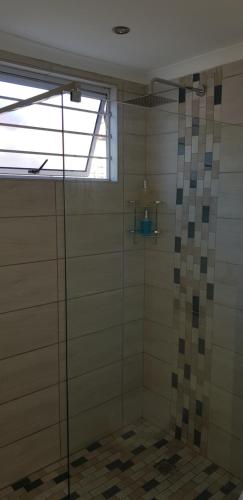 a shower with a glass door in a bathroom at The Studio on Balmoral in Durban