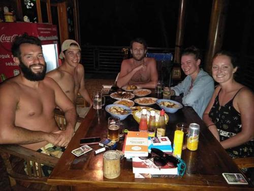 a group of men sitting around a table with food at Arrys Watukarung Surfcamp in Kalak