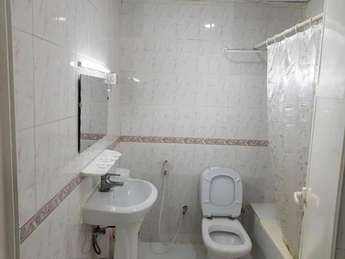 a white bathroom with a toilet and a sink at Sophin Hotel in Sharjah