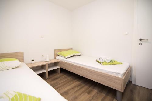 2 letti in una camera con pareti bianche e pavimenti in legno di Luxury Mobile Homes Liza2 a Biograd na Moru