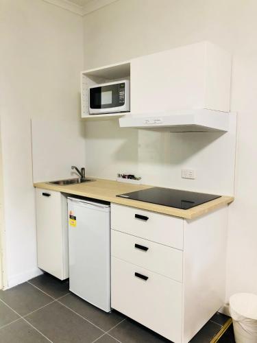 a kitchen with white cabinets and a microwave at Parkdale Motor Inn in Parkdale