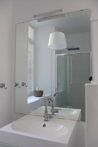 une salle de bain blanche avec un lavabo et un miroir dans l'établissement L'authentique - Coeur de ville, à Toulouse