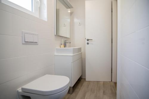 a white bathroom with a toilet and a sink at Luxury Mobile Homes Liza2 in Biograd na Moru