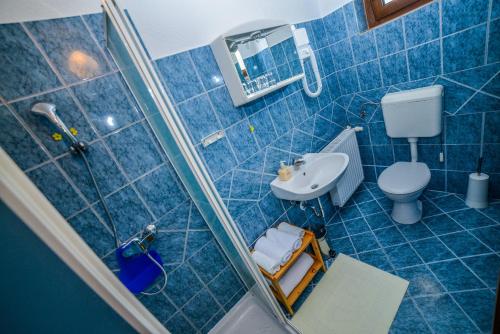 a blue tiled bathroom with a toilet and a sink at Sixteen Lakes Guest House in Jezerce