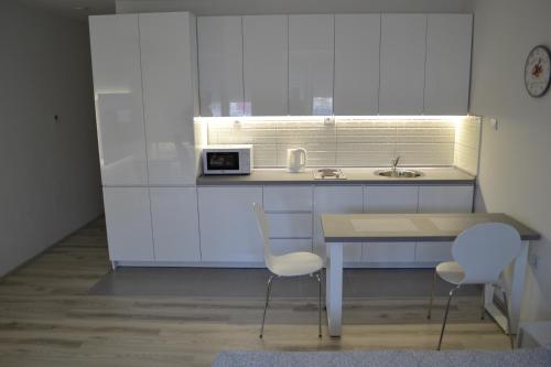 斯科普里Lazarus Studio Apartment的厨房配有桌子、两把椅子和微波炉