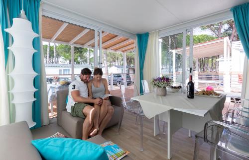 a man and woman sitting on a couch in a living room at Ca' Pasquali Village in Cavallino-Treporti