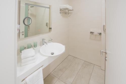 a white bathroom with a sink and a mirror at Hotel Rimo in Ort im Innkreis