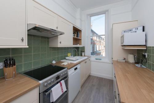 a kitchen with white cabinets and green tiles at Spacious one bedroom apartment with a sofa bed offering a sea view sleeps four in Broadstairs