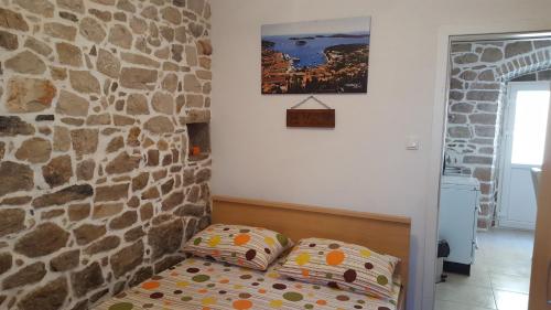 a bedroom with a bed in a stone wall at Holiday House Popovic in Sućuraj