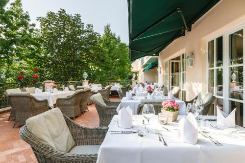 a restaurant with white tables and chairs on a patio at Hotel Pienzenau Am Schlosspark in Merano
