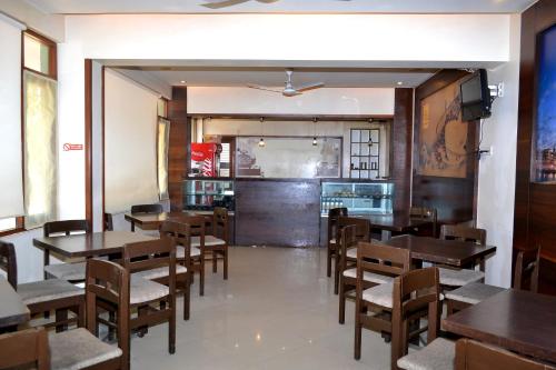 comedor con mesas y sillas de madera en Jaffer Bhai's Brickland Hotel, en Panchgani