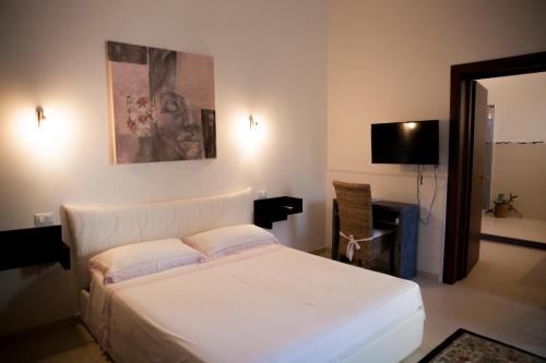 1 dormitorio con 1 cama blanca y TV en B&B Fiori di Loto, en Corigliano d'Otranto