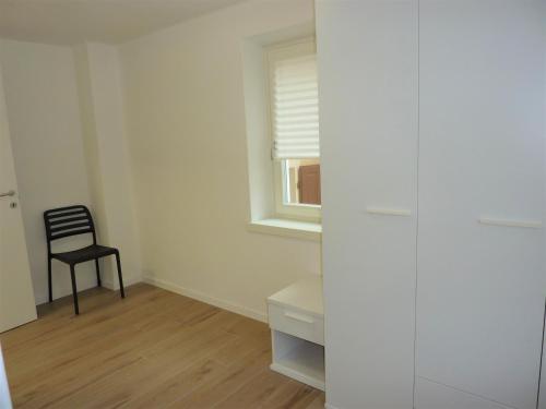 a white room with a chair and a window at Trentino Apartments - Casa ai Tolleri in Folgaria