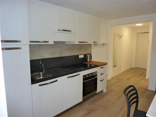 a kitchen with white cabinets and a sink at Trentino Apartments - Casa ai Tolleri in Folgaria
