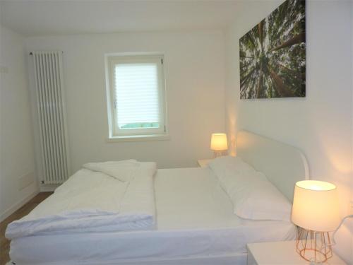 a white bed in a room with two lamps at Trentino Apartments - Casa ai Tolleri in Folgaria
