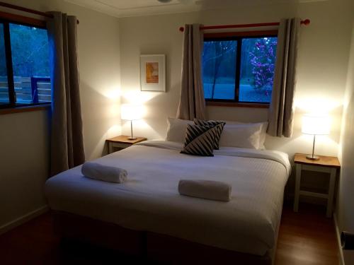 um quarto com uma cama com 2 candeeiros e 2 janelas em Wild Woods at Pokolbin em Pokolbin