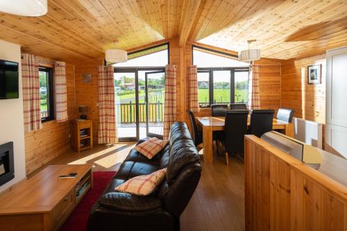 a living room with a leather couch and a table at Linwater Holiday Park in Newbridge